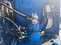 Close-up of a blue hydraulic system with various hoses and valves attached to a machine component, part of a Genie S-65 4X4 model from 1997
