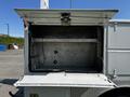 The image shows the open compartment of a 2004 Freightliner M2 revealing a metal storage area with faint wiring and two mounting brackets inside