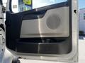 Driver's side door of a 2005 Volvo VND 122 featuring a speaker and armrest with a simple design in light and dark shades
