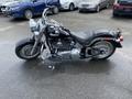A black 2008 Harley-Davidson FLSTFI motorcycle with chrome accents and a classic design is parked on a wet surface