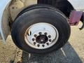 Close-up of a front tire and wheel of a 2013 International 4300 truck featuring a white rim and a Bridgestone tire with visible tread and bolts