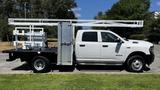 A 2019 RAM 3500 truck with a flatbed and equipment rack on the back is parked on a grassy area