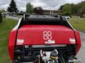 A red and black 2020 Pottinger Impress baler with warning labels and a large roller on top