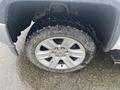 Close-up of a silver wheel with a GMC emblem mounted on a rugged tire with a deep tread pattern