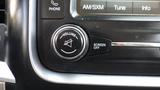 A close-up view of the volume control knob and buttons for phone, AM/SXM, tune, and info on the dashboard of a 2014 RAM 5500