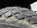 Close-up of the tire of a 2011 Kubota M8540D with a worn tread pattern showcasing distinctive rectangular lugs and some dirt along the surface