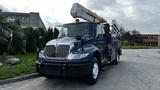 A blue 2009 International 4300 utility truck with a raised aerial lift and side compartments for tools and equipment