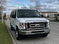 A 2014 Ford Econoline van with a shiny silver exterior parked on the side of the road