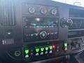 Dashboard of a 2017 Chevrolet Express featuring a radio display climate controls and various buttons including a set of green operational buttons