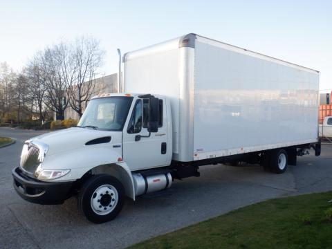 A 2014 International Durastar box truck with a white cab and large cargo area parked on a street