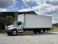 A 2022 International MV607 truck with a white boxy cargo area is parked on a pavement, showcasing its side profile and front view