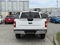 A 2018 Ford F-150 viewed from the rear showcasing its white exterior and distinctive tailgate with the Ford logo