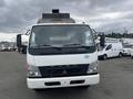 A 2008 Mitsubishi Fuso FE180 truck facing forward with a white and gray color scheme and orange warning lights on the roof