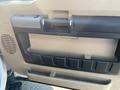 The interior door panel of a 2014 Ford F-350 SD featuring a handle and storage compartment in a beige and black color scheme