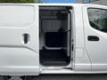 A white 2020 Nissan NV200 van with an open side door revealing a spacious interior designed for cargo transport