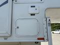 A white panel on a 2018 Westland Travelaire showcasing a small door with a lock and labels indicating fresh water and city water connections