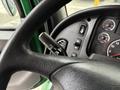 A close-up of the steering wheel and control panel of a 2015 Freightliner M2 106 showing a turn signal stalk and various gauges and buttons