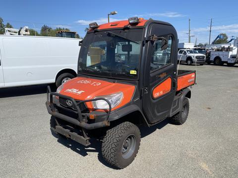 A 2018 Kubota ATV with an orange and black design featuring a cabin equipped with headlights and a flatbed for cargo transport