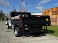 A 2021 Ford F-550 truck with a flatbed and wooden cargo in the back parked on a street