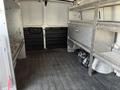 A 2014 Chevrolet Express van interior featuring metal shelving units and a smooth rubber floor with a storage bag in one corner
