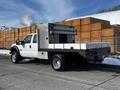 A 2011 Ford F-450 Super Duty truck with a flatbed and metal tool storage box in the rear, prominently displayed from the side