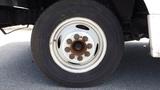 A close-up of a tire mounted on a white wheel with multiple bolts from a 2011 Ford Econoline