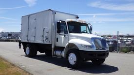 A white 2011 International DuraStar 4300 truck with a box cargo body and side door parked on a surface