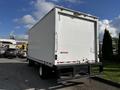 A 2016 Isuzu NPR box truck with a white enclosed cargo area and a black rear bumper