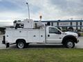 A 2016 Ford F-550 utility truck with a white exterior is equipped with a ladder and various tools mounted on the truck bed