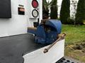 A blue bench vise mounted on the bed of a 2015 Ford F-550 truck