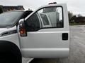 A white 2014 Ford F-550 truck with an open driver's side door and visible amber roof lights