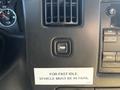 A dashboard control panel of a 2017 Chevrolet Express featuring buttons for various functions and a warning label about vehicle idle settings