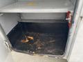 Interior view of a compartment in a 2003 Ford F-450 SD showing a metal shelf above and a stained, rusted floor with debris and discoloration