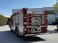 A red 2006 Emergency One fire truck with multiple storage compartments and hoses visible on the back panel