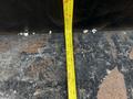 A measuring tape laid across a surface near a 2021 Ford F-550 showing measurements along its length