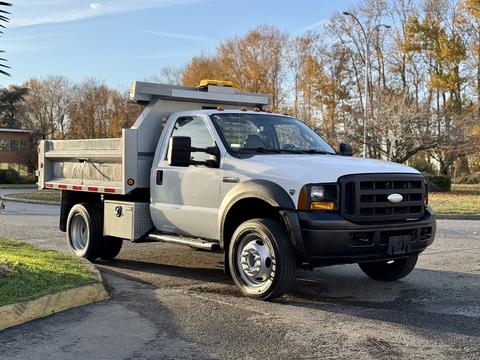 A white 2006 Ford F-550 pickup truck with a flatbed and tool compartment attached in the back
