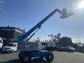 1997 Genie S-65 4X4 articulating boom lift with a raised platform and extended arm positioned upward