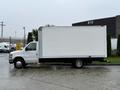 A white 2013 Ford Econoline box truck with a closed cargo area and black accents parked on a wet surface
