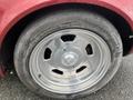 Close-up of a vintage 1970 Chevrolet Corvette wheel featuring a polished alloy rim with a central logo and a worn tire showing visible tread patterns