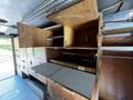 Interior of a 2009 Morgan Olson Workhorse featuring wooden cabinets and shelves with various compartments and a flat workspace