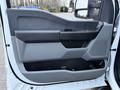 A close-up view of the door panel of a 2023 Ford F-250 featuring a sleek design with various controls and armrest in contrasting colors