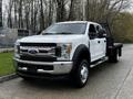 A 2017 Ford F-550 truck with a flatbed design featuring a white exterior chrome front grille and large wheels parked at an angle