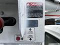 A close-up of a control panel with warning labels and buttons for upper and lower controls on a 2013 International DuraStar vehicle