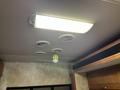 Ceiling light fixture with a yellow pendant lamp and four air vents in an RV interior setting