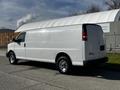 A white 2015 Chevrolet Express cargo van parked with its side view visible showcasing the rear door and wheels