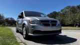 A 2016 Dodge Grand Caravan in silver color parked with a slight angle showing the front and side view