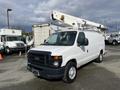A 2008 Ford Econoline van with a ladder rack mounted on top parked in an outdoor area