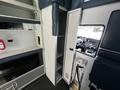 A 2013 Chevrolet Express interior featuring a cabinet with shelves and the driver's seat visible through the open door
