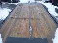 A flatbed trailer with a wooden surface showing dirt and debris