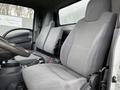 Interior view of a 2022 Isuzu NPR featuring two gray upholstered seats and a steering wheel in the foreground